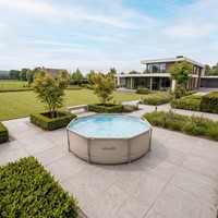 Lifestyle sfeerimpressie van het ronde VirtuFit frame zwembad diameter 366 cm geplaatst op een modern betegeld terras in een ruime tuin.
