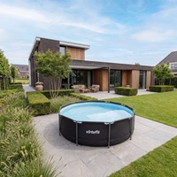 Lifestyle sfeerimpressie van het ronde antracietkleurige VirtuFit frame zwembad diameter 305 cm geplaatst op een modern betegeld terras in een strak ingerichte tuin bij een luxe woning.