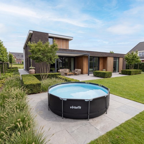 Sfeerbeeld van het ronde VirtuFit opzet zwembad antraciet op een modern terras in een grote, luxe tuin.